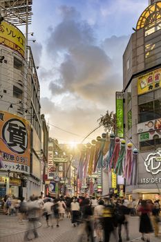 Sunset sky on Shibuya Center Gai Street which literally means Shibuya Central District. The busiest street once intersected with Shibuya Station, it stretches for 350 meters and incorporates the adjacent streets of Bunkamura, Inokashira and Utagawa into its neighborhood. In 2011 the street was renamed Basketball Street in reference to the holy place of Japanese basketball which is the Yoyogi National Gymnasium to which this street leads. The photo is taken in summer at the Tanabata Star Festival where the portal is adorned with paper decorations in the shape of shooting stars for the occasion.