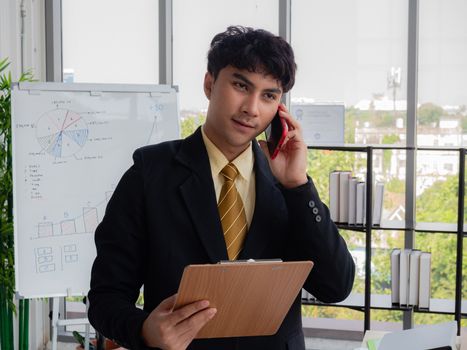 A young Asian businessman is reporting the company's performance to shareholders in a modern office.