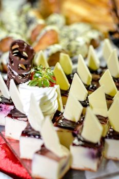 Tray full of cupcakes and slices of cake inside a buffet