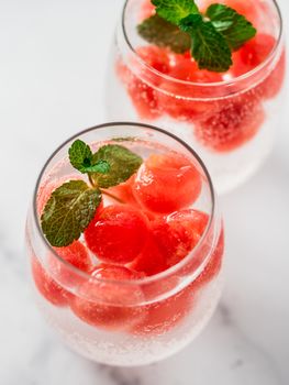 Watermelon ice with sparkling water or soda in glass tumbler. Summer party idea and recipe, add color and flavor for soda or other drink. Vertical