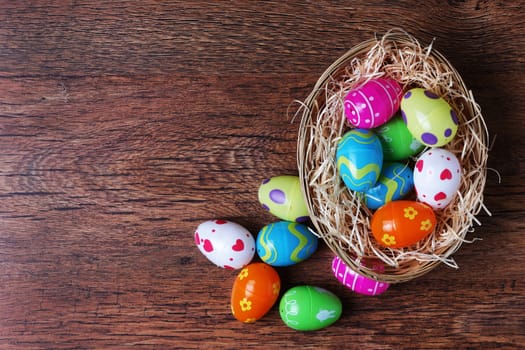 A basket with straw on wood with toy easter eggs and copy space
