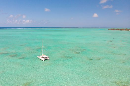 Catamaran sailing boat in turquoise sea lagoon on tropial Mauritius island. Aerial, top down drone view.