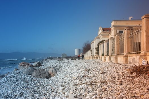 sea ​​with sandy beach and rocks with a view of the fiat tower in massa carrara in tuscany in front of the don gnocchi hospital in italy