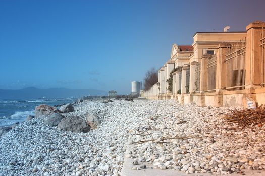 sea ​​with sandy beach and rocks with a view of the fiat tower in massa carrara in tuscany in front of the don gnocchi hospital in italy