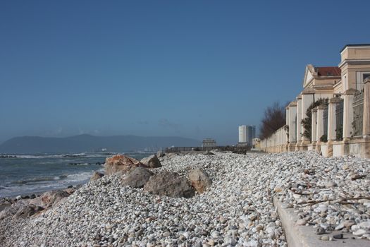 sea ​​with sandy beach and rocks with a view of the fiat tower in massa carrara in tuscany in front of the don gnocchi hospital in italy