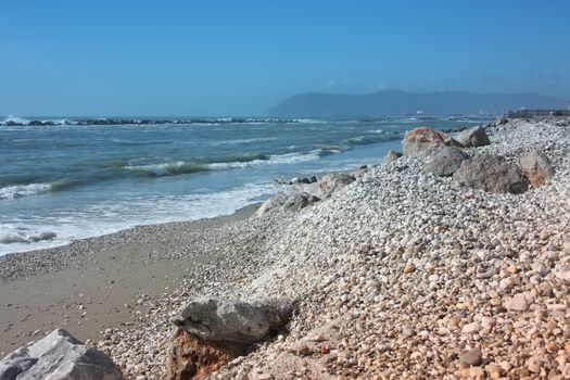 sea ​​with sandy beach and rocks with a view of the fiat tower in massa carrara in tuscany in front of the don gnocchi hospital in italy