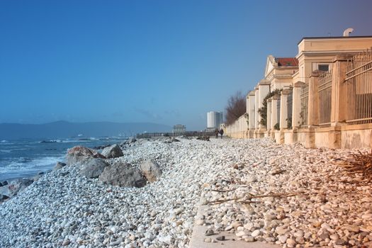 sea ​​with sandy beach and rocks with a view of the fiat tower in massa carrara in tuscany in front of the don gnocchi hospital in italy
