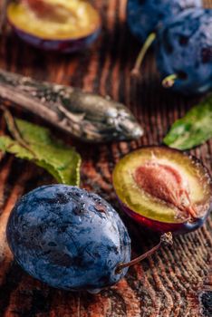 Ripe plums on wooden table with leaves, water drops and vintage knife