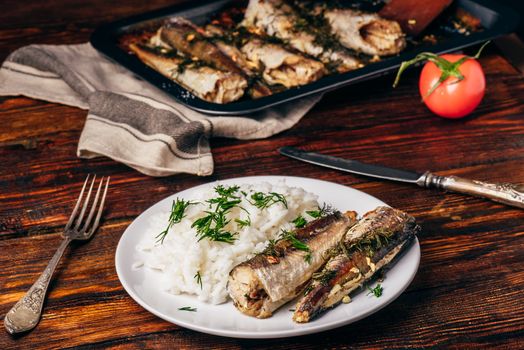 Baked hake carcasses with rice on white plate