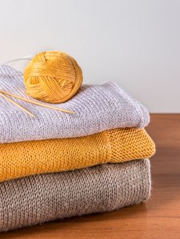 skein of yarn, knitting needles on knitwear on wooden table