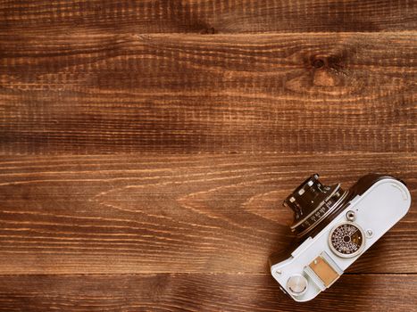 Wooden table background with old vintage camera. Flat lay or top view