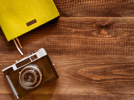 top view vintage old camera and notebook on wooden background
