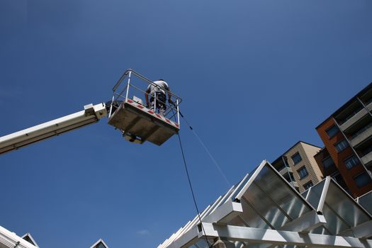 worker of Professional Facade Cleaning Services washing a glass roof with blue sky