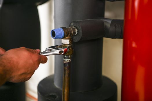 man fixing a pipe with a wrench with a hand showing