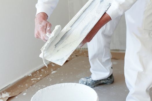 Plasterer stirring plaster in a bucket. With hands and legs showing