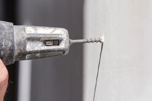 Plasterer screwing sheetrock to a wall, With white copy space