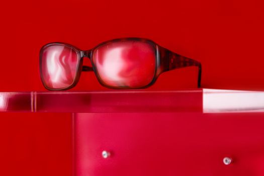 glasses on a plexiglass display with red background and copy space