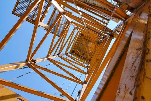yellow crane shot from inside with blue sky. Shot from below