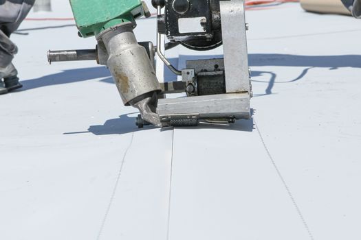 roofer joining white plastic sheets. with white roof
