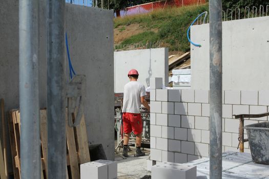 Hard working people at construction site. Worker with helmet and red pants