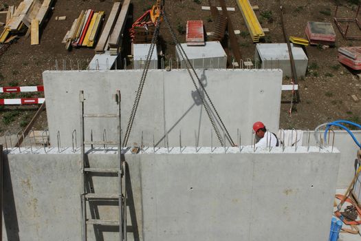 Hard working people at construction site. Worker with helmet and red pants