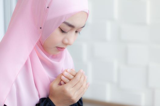 Young Asian Muslim Women Praying to Allah in peace, wearing a pink hijab.