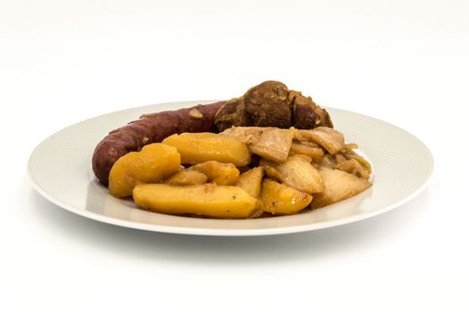 Plate of burnt white cabbage with sausage, potatoes and a piece of lamb on a white background