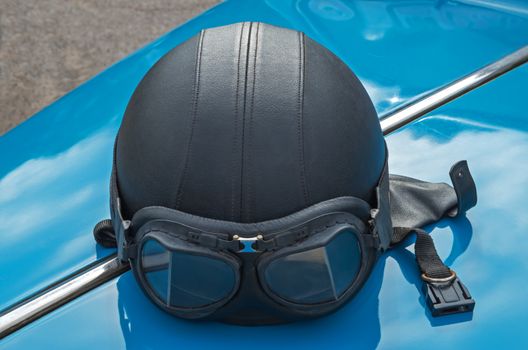 Motorcycle helmet with skin lies on the hood of a retro car.
