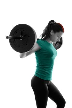 Fit attractive young woman working out with a barbell, looking down, backlit silhouette studio shot isolated on white background. Fitness and healthy lifestyle concept.