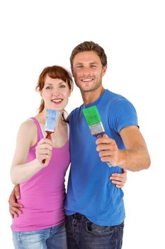 Couple both holding paint brushes on white background