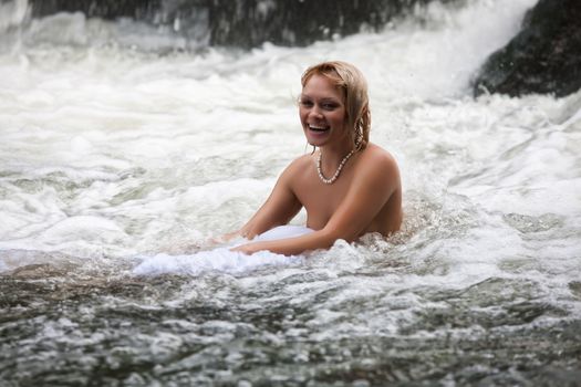 Young naked woman swimming in a river