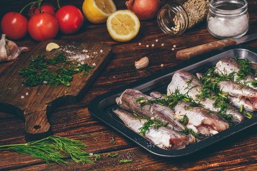 Hake carcasses on baking sheet with vegetables and spices