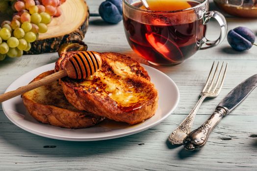 Healthy breakfast concept. French toasts with honey, fruits and tea over white wooden background