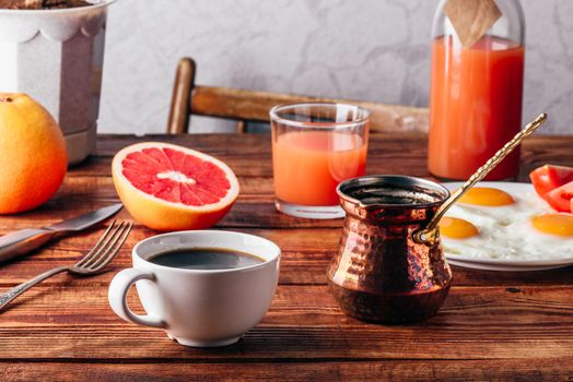 Breakfast with turkish coffee, fried eggs, juice and fruits over wooden table