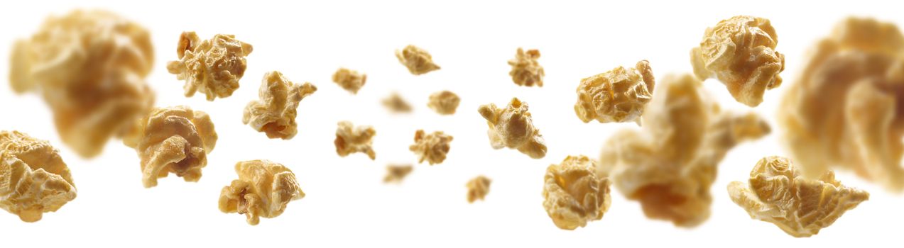 Caramel-flavored popcorn levitates on a white background.