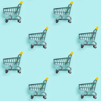 Shopping cart staggered on blue background. Seamless pattern. Top view or flat lay. Shop trolley seamless pattern as sale, discount, shopaholism concept. Consumer society trend.