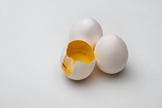 two ful egg, on egg with it’s top crack open, exposed inside skin and yoke