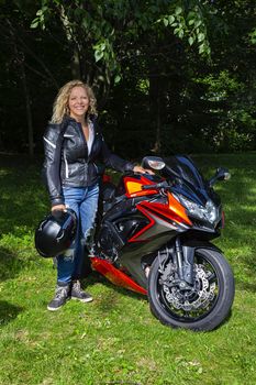 twenty something blond woman, wearing motocycle clothing, standing in front of a sport motocycle
