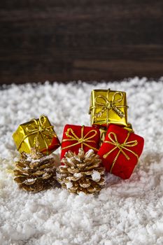gold and red present with decorative pine cone in the snow