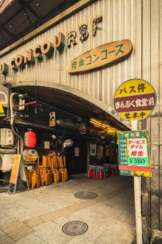 Restaurant sign immitating an old retro bus stop sign on underpass Yurakucho Concourse wall under the railway line of the station Yurakucho. Japanese noodle stalls and sake bars revive the nostalgic years of Showa air with old posters and placards glued to the walls of the tunnel.