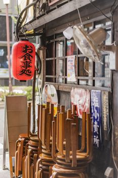 Old vintage retro japanese metal signs and red rice paper lantern where it is written "Oshokujidokoro" which means "Meal" on underpass Yurakucho Concourse wall under the railway line of the station Yurakucho. Japanese noodle stalls and sake bars revive the nostalgic years of Showa air with old samurai posters and placards glued to the walls of the tunnel.