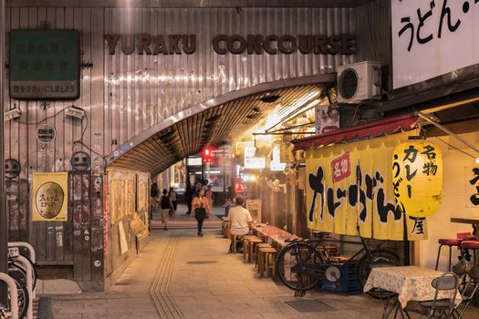 Night view of Yurakucho Concourse underpass under the railway line of the station Yurakucho. Japanese noodle stalls and sake bars revive the nostalgic years of Showa air with old posters and placards glued to the walls of the tunnel.