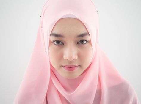 Close up Portrait of a beautiful Muslim Asian woman in a pink hijab on white background.