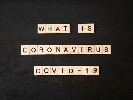 what is coronavirus COVID-19 words made of wood block. What is coronavirus COVID-19 text on dramatic atmosphere black wooden table. Coronavirus concept top view.