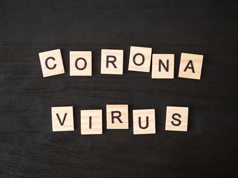 Coronavirus word made of wood block. Coronavirus text on dramatic atmosphere black wooden table. Coronavirus concept top view.