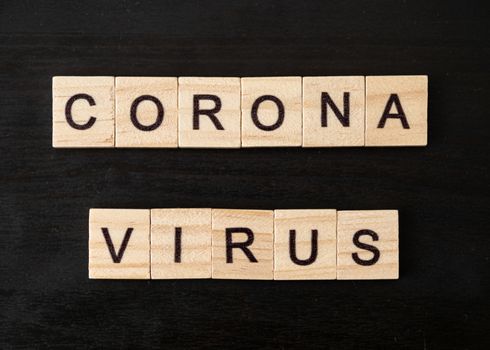 Coronavirus word made of wood block. Coronavirus text on dramatic atmosphere black wooden table. Coronavirus concept top view.
