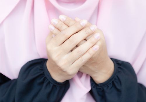 Young Asian Muslim Women Praying to Allah in peace, wearing a pink hijab.