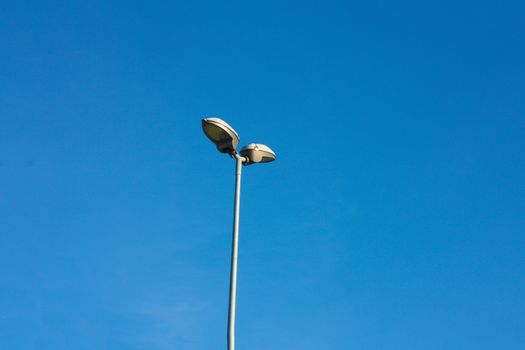 slim and lonely lamppost in contrast against the clear blue sky without clouds