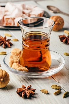 Tea in arab glass with turkish delight Rahat Lokum and different spices over wooden surface