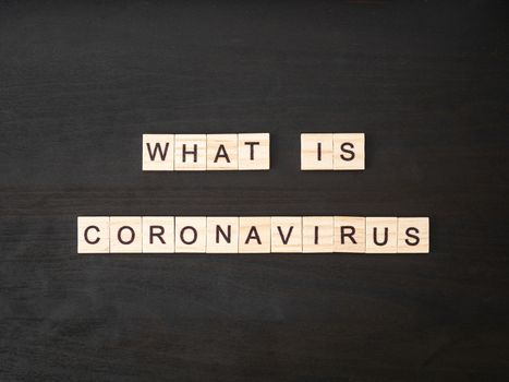 what is coronavirus words made of wood block. What is coronavirus text on dramatic atmosphere black wooden table. Coronavirus concept top view.